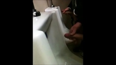 two slim dicks getting wanked at the urinals
